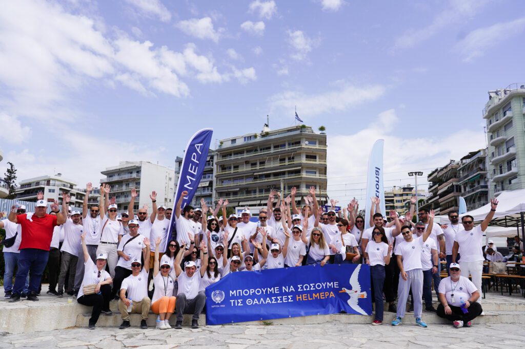 A group of employees posing happily with their hands in the air, after finishing a voluntary beach clean-up.