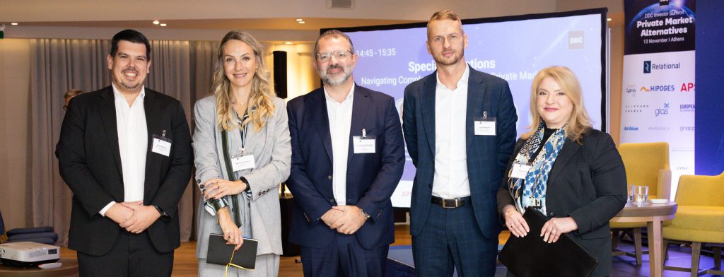 A group of speakers at a conference posing at the camera and smiling.