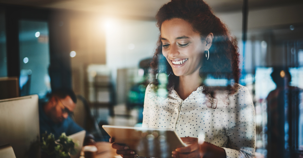 A woman looking at a tablet in an office setup.